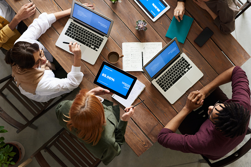 a group of people sitting at a table with laptops